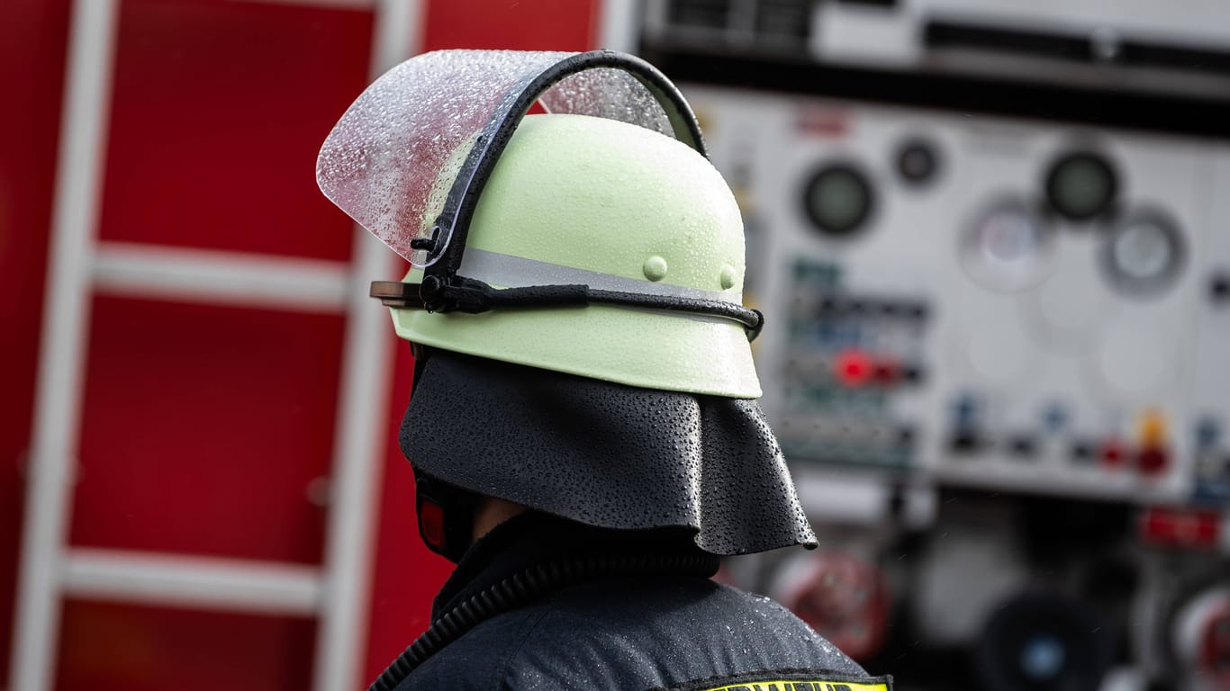 Ein Feuerwehrmann steht mit Schutzkleidung und Helm vor einem Einsatzfahrzeug (Symbolbild): Ein zu kleines und vor allem marodes Feuerwehrhaus macht Einsatzkräften in Nürnberg zu schaffen.