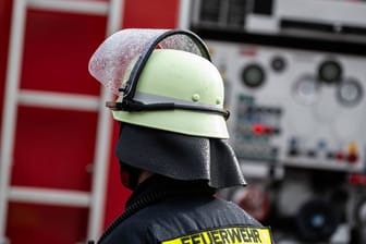 Ein Feuerwehrmann steht mit Schutzkleidung und Helm vor einem Einsatzfahrzeug (Symbolbild): Ein zu kleines und vor allem marodes Feuerwehrhaus macht Einsatzkräften in Nürnberg zu schaffen.