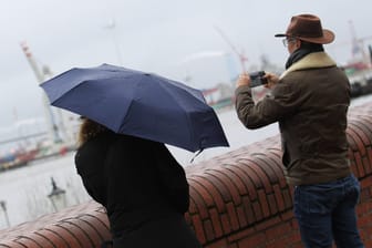 Ein Paar steht mit Regenschirm am Jungfernstieg (Symbolbild): Am Donnerstagabend kann ein Sturm in Hamburg aufziehen.