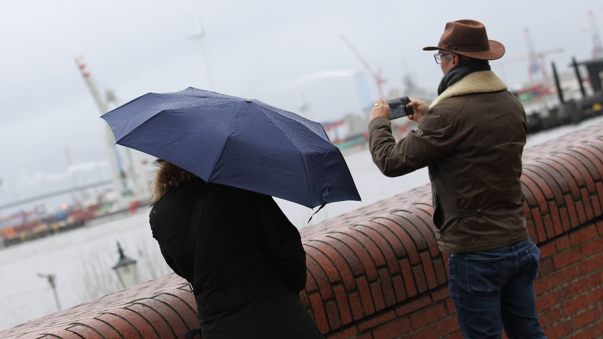 Ein Paar steht mit Regenschirm am Jungfernstieg (Symbolbild): Am Donnerstagabend kann ein Sturm in Hamburg aufziehen.