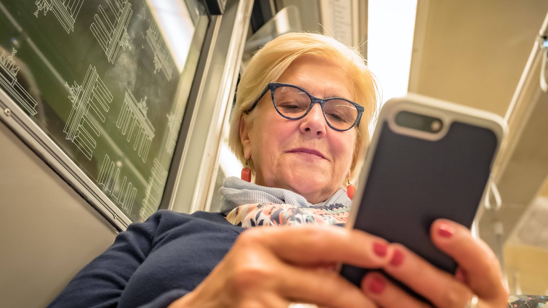 Eine Frau mit ihrem Smartphone in der Hand (Archivbild): Das Handynetz in der Berliner U-Bahn soll endlich für alle besser werden.