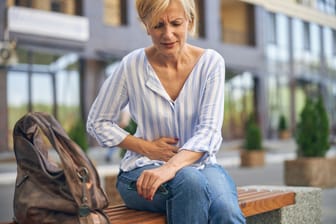 Eine Frau fasst sich an den Bauch: Zeigen sich beim Sjögren-Syndrom Darmprobleme, kann ein Zusammenhang mit der Autoimmunerkrankung bestehen.