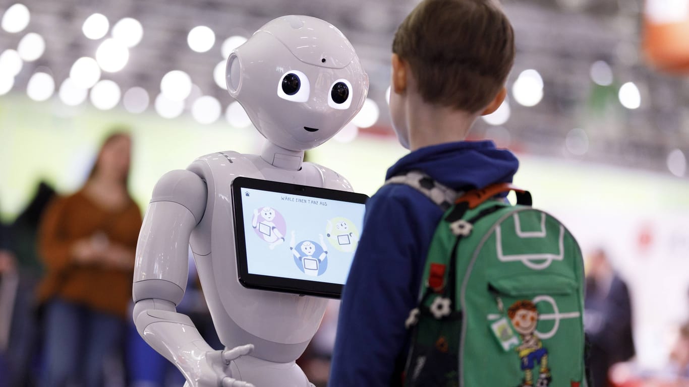 Roboter und Schüler auf einer Bildungsmesse (Archivbild): Ab welchem Alter sollte KI im Unterricht eine Rolle spielen?
