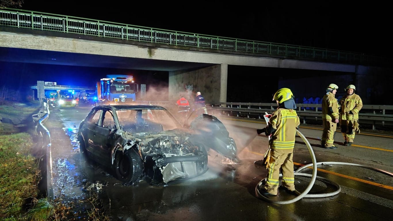 Die Feuerwehr löscht ein brennendes Fahrzeug nach einem Unfall auf der A1 bei Wildeshausen. Ein Autofahrer war mit einem Sattelzug zusammengeprallt.