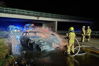 Die Feuerwehr löscht ein brennendes Fahrzeug nach einem Unfall auf der A1 bei Wildeshausen. Ein Autofahrer war mit einem Sattelzug zusammengeprallt.