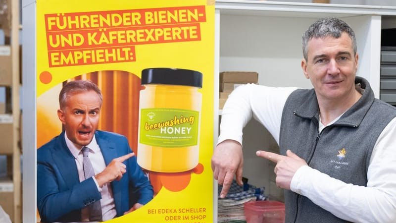 Imker Rico Heinzig neben einem Plakat mit dem Foto des Moderators Jan Böhmermann: