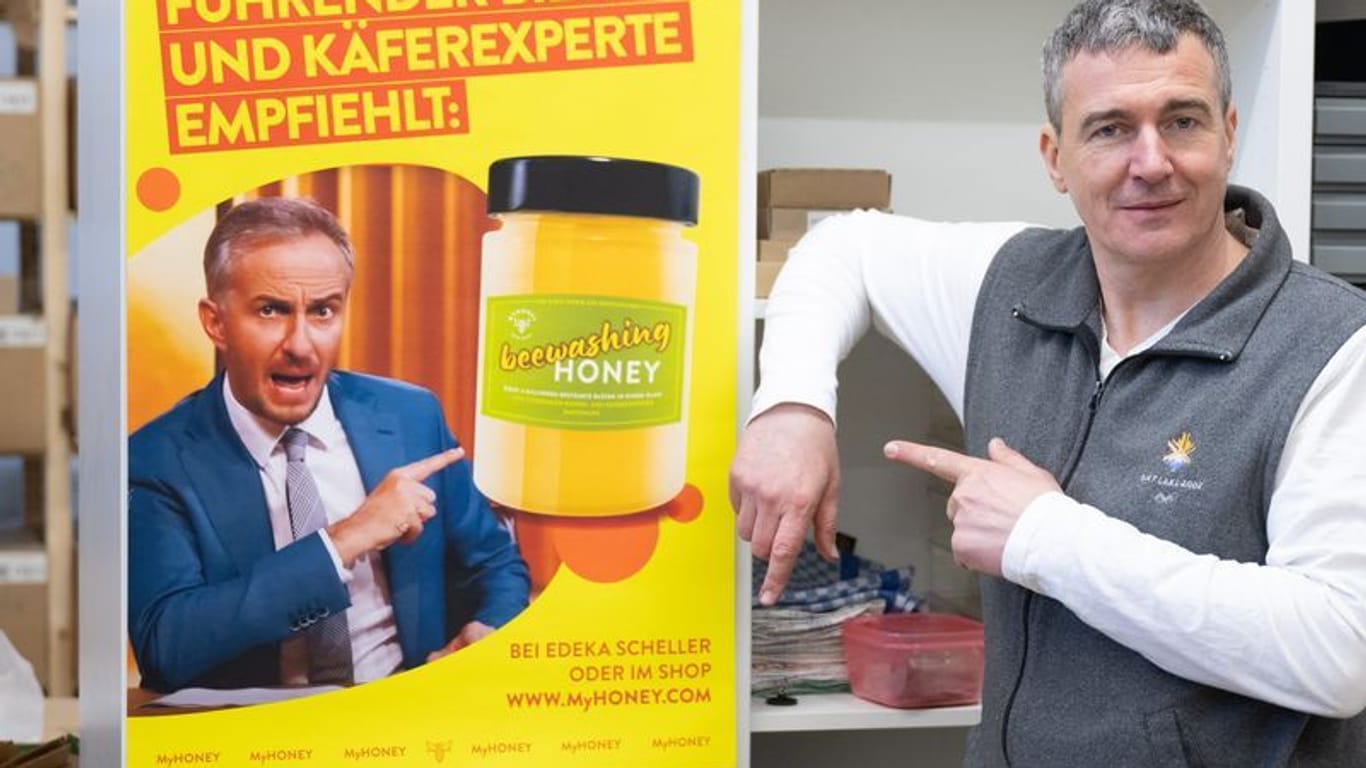 Imker Rico Heinzig neben einem Plakat mit dem Foto des Moderators Jan Böhmermann: