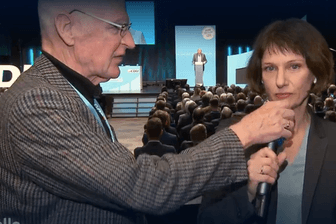 Ein Mann greift NDR-Reporterin Katharina Seiler bei einer CDU-Regionalkonferenz ins Mikrofon.