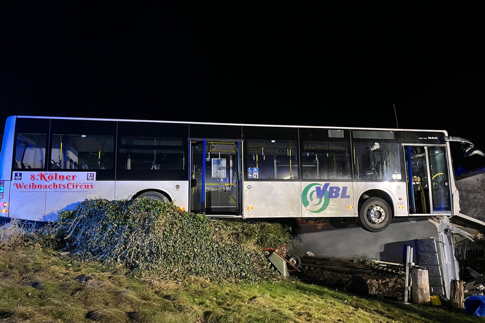 Ein verunfallter Bus hängt nach einem Unfall nahezu in der Luft auf den Trümmern einer Garage.