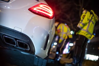 Polizisten kontrollieren ein hochmotorisiertes Auto (Symbolbild): Das Treffen in Freising wurde nach dem Vorfall von der Polizei aufgelöst.