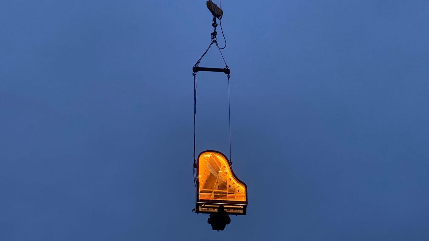 Während der Blauen Stunde, also dem Zeitraum kurz vor dem Sonnenaufgang, spielt der Künstler Alain Roche in zehn Metern Höhe auf seinem Klavier. Beide hängen dabei vertikal an einem Kran.