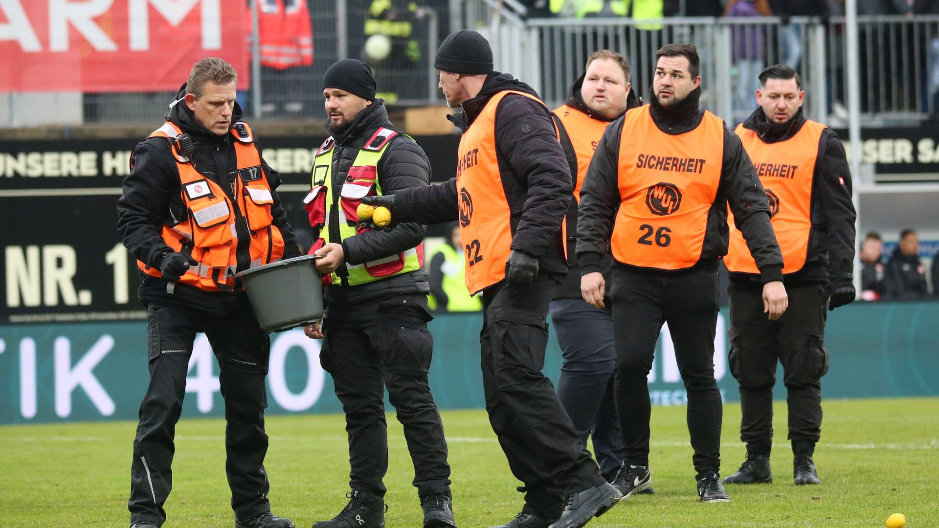 Sicherheitskräfte in Elversberg: Ordner sammeln Zitronen auf.