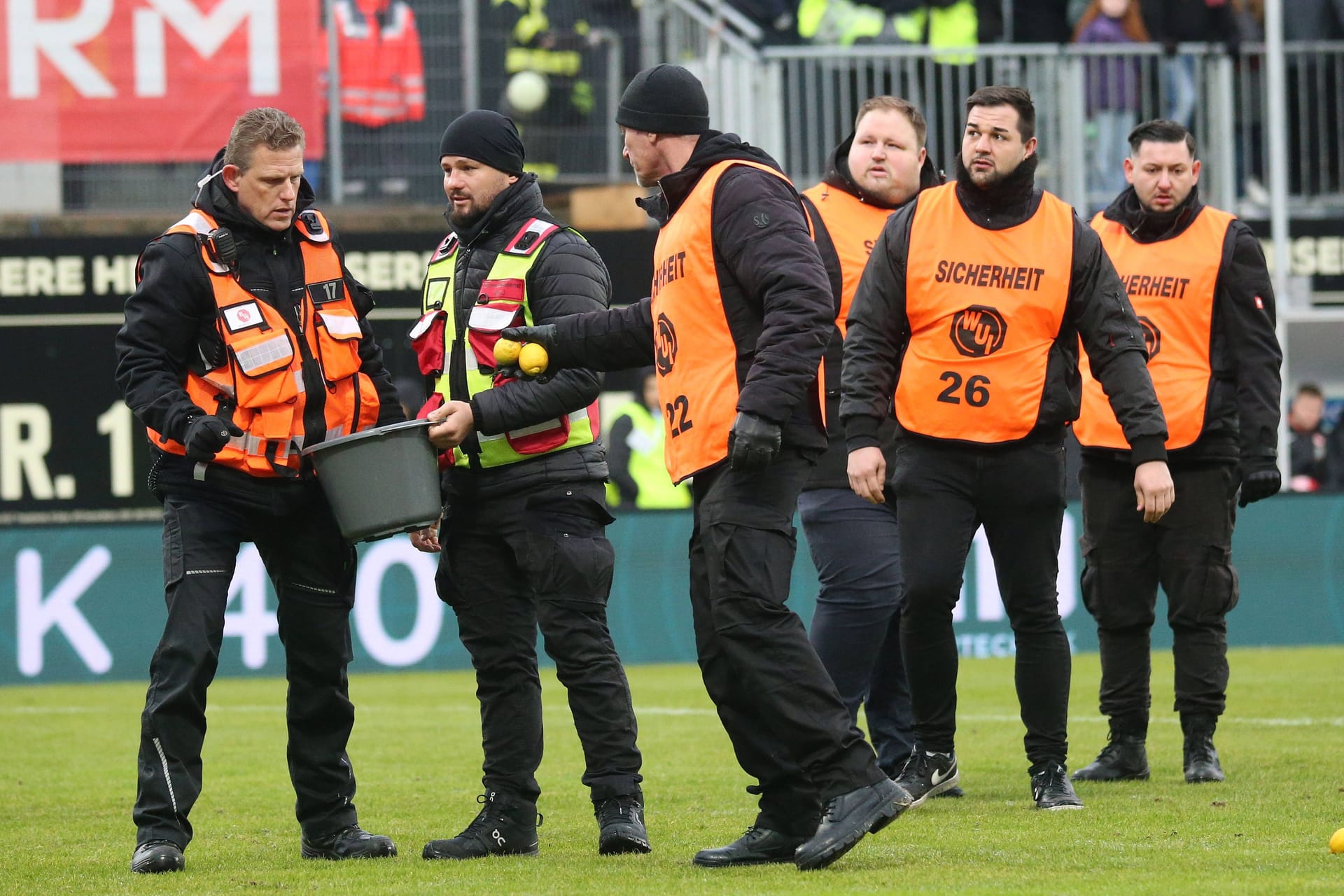 Sicherheitskräfte in Elversberg: Ordner sammeln Zitronen auf.