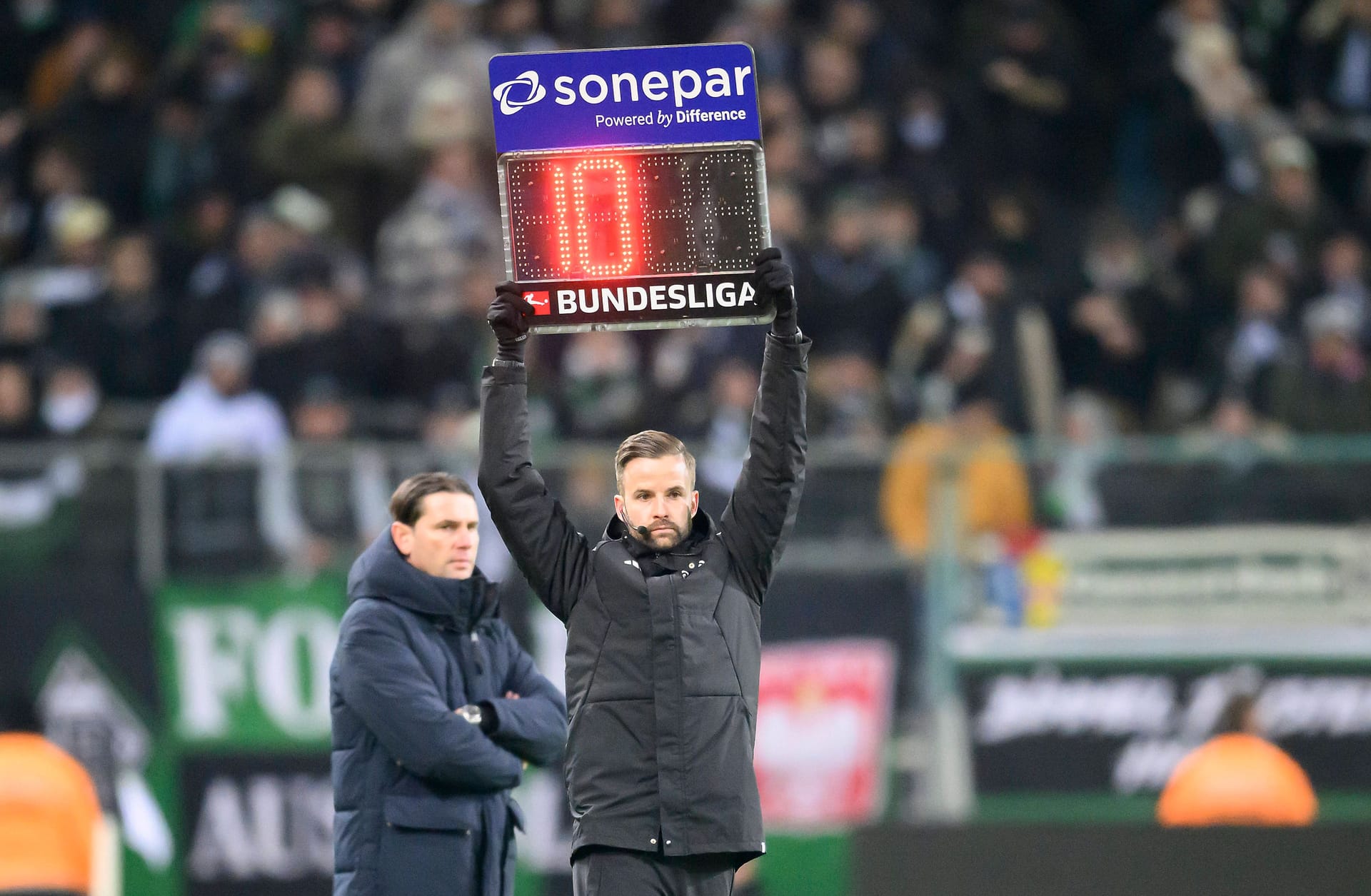 Borussia Mönchengladbach gegen FC Augsburg: Nach dem Protest der Fans gegen die DFL hebt der vierte Offizielle Michael Bacher die Tafel hoch und zeigt zehn Minuten Nachspielzeit an.