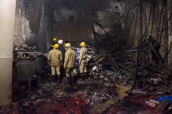 Feuerwehrleute schauen zu, nachdem sie am späten Donnerstag ein Feuer in einer Farbenfabrik im Stadtteil Alipur im Norden von Neu-Delhi, Indien, gelöscht haben.