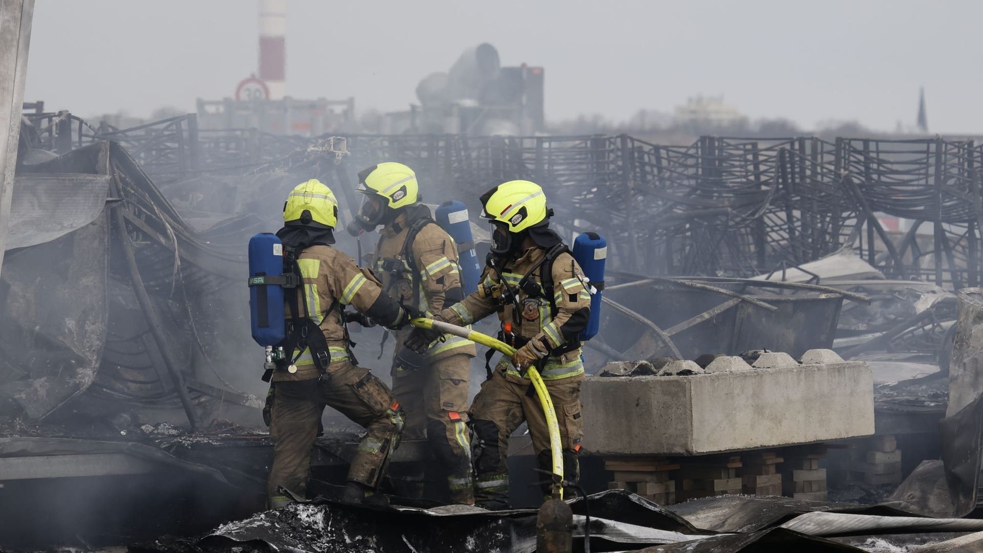 Die Feuerwehr löscht die Brandstelle bei Flüchtlingsunterkunft am ehemaligen Flughafen Tegel: Ein Zelt stand hier im Brand.