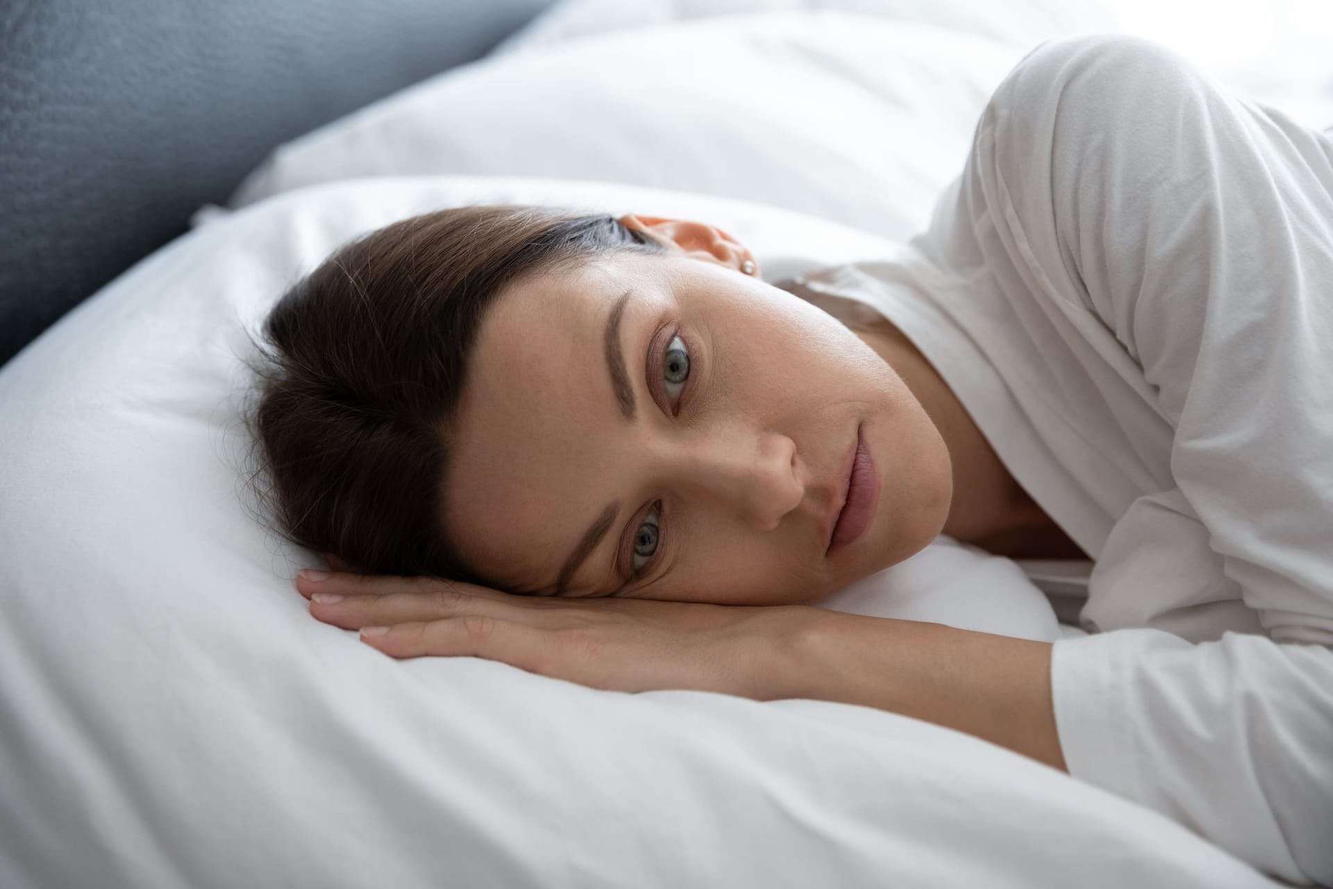 Junge Frau liegt im Bett und denkt nach.