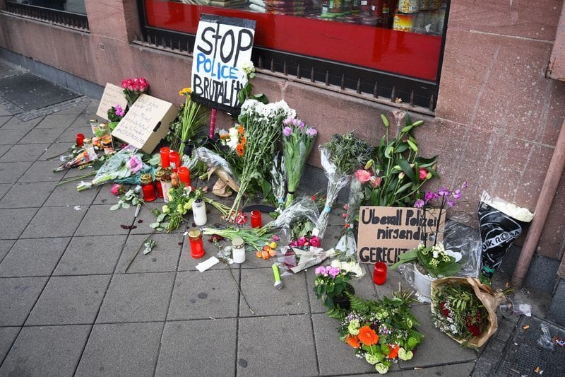 Blumen, Kerzen und Schilder liegen und stehen an dem Ort, an dem ein Mann nach einer Polizeikontrolle gestorben ist: Ein Gericht sprach nun einen der Beamten frei.