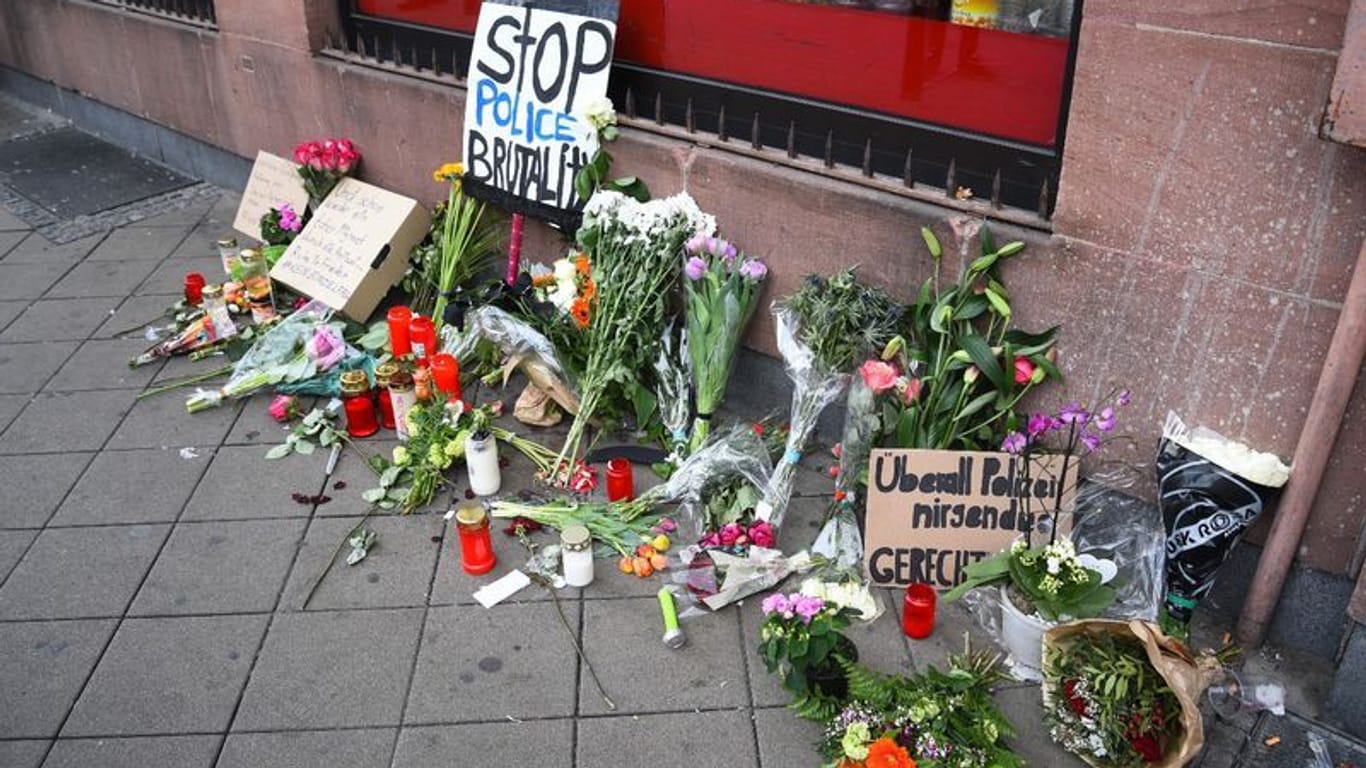 Blumen, Kerzen und Schilder liegen und stehen an dem Ort, an dem ein Mann nach einer Polizeikontrolle gestorben ist: Ein Gericht sprach nun einen der Beamten frei.