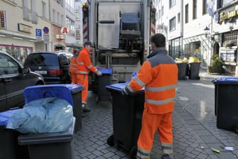 Mitarbeiter der AWB leeren die Mülltonnen (Symbolbild): In Köln verschieben sich in den kommenden Tagen die Leerungstage.