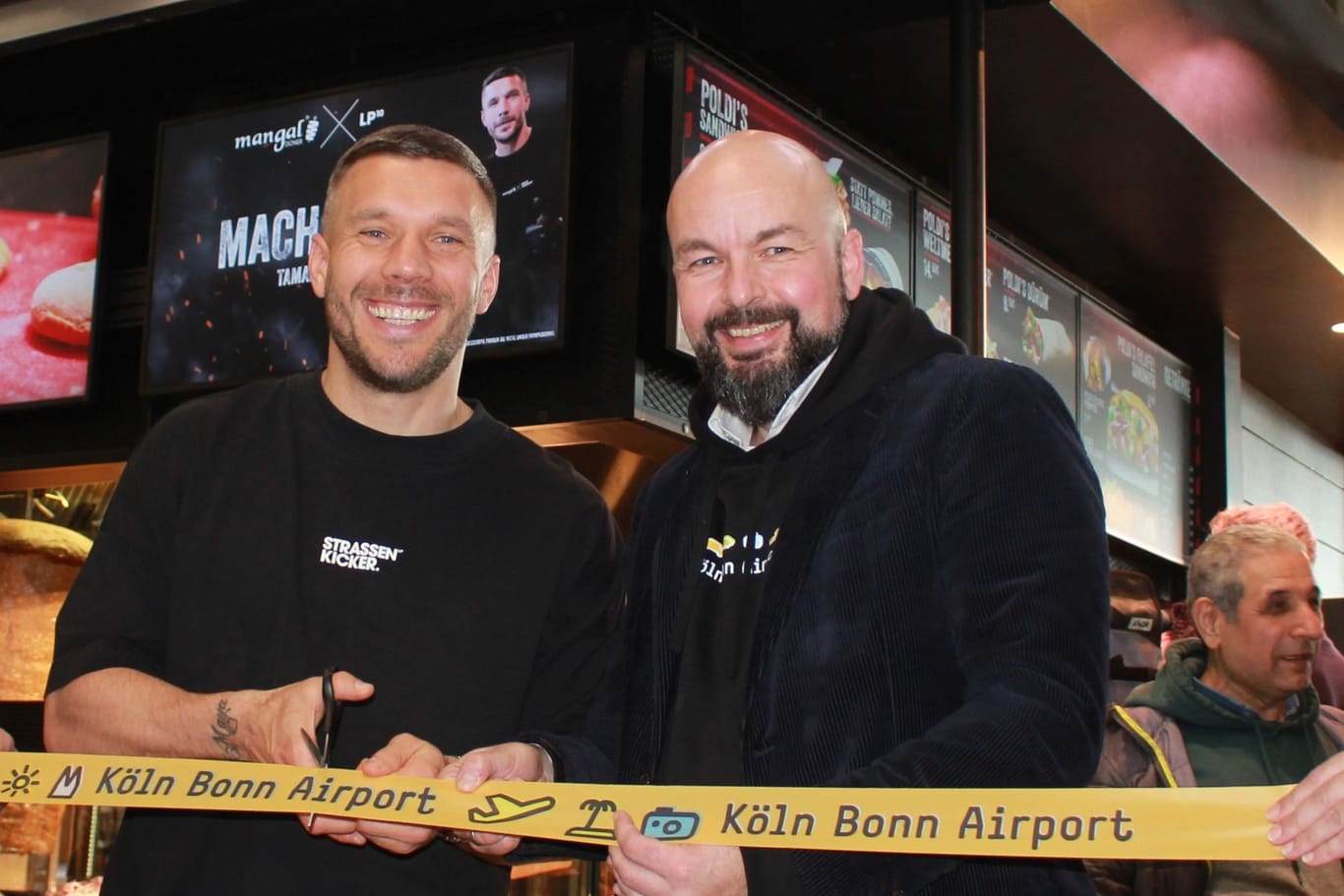 Lukas Podolski mit Flughafen-Chef Schmid: Es ist die 13. Filiale in Köln.