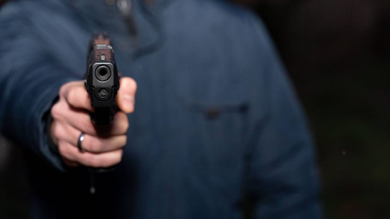 Mann hält eine Pistole (Symbolfoto): In Duisburg sind am Morgen bewaffnete Unbekannte in ein Haus eingebrochen.