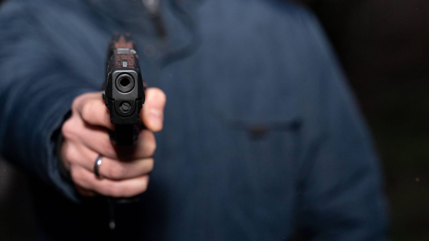 Mann hält eine Pistole (Symbolfoto): In Duisburg sind am Morgen bewaffnete Unbekannte in ein Haus eingebrochen.