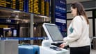 Eine Frau steht an einem "self bag drop"-Schalter am Flughafen Nürnberg. In Zukunft sollen Reisende ihr Gepäck bei zwei Airlines selber aufgeben können