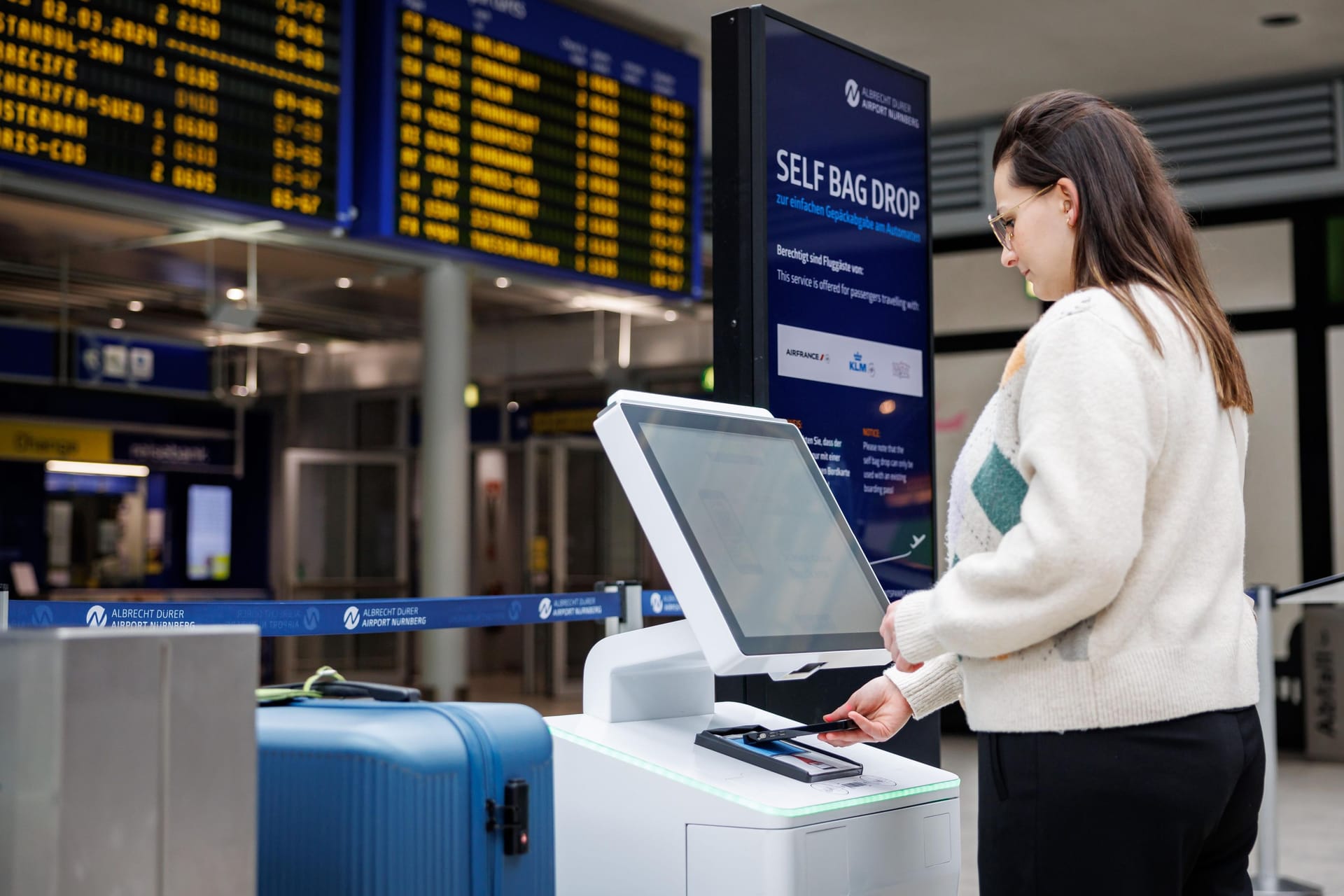 Eine Frau steht an einem "self bag drop"-Schalter am Flughafen Nürnberg. In Zukunft sollen Reisende ihr Gepäck bei zwei Airlines selber aufgeben können