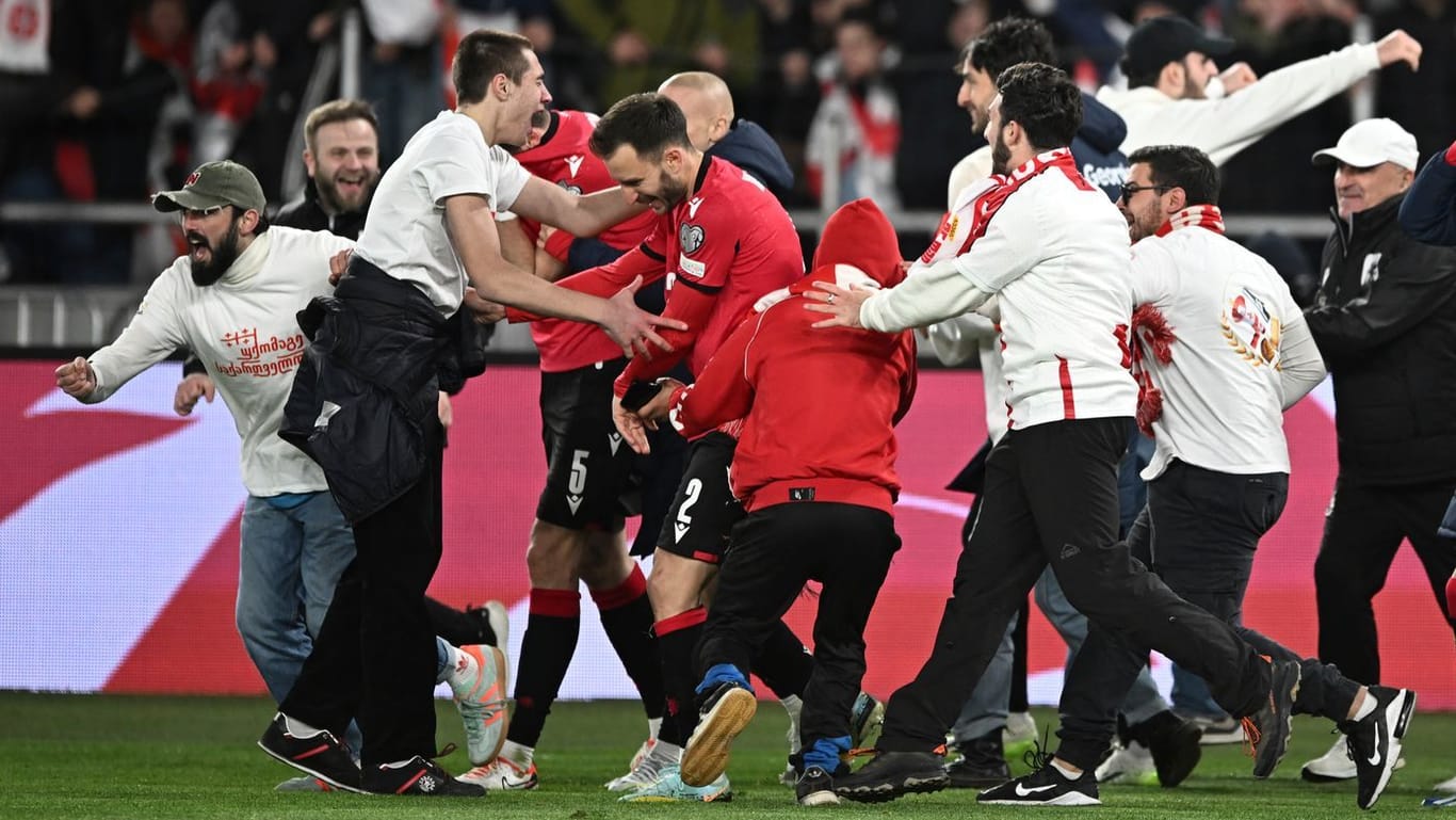 Unbändige Freude: Georgiens Nationalspieler (M.) feiern mit auf den Platz gestürmten Fans.