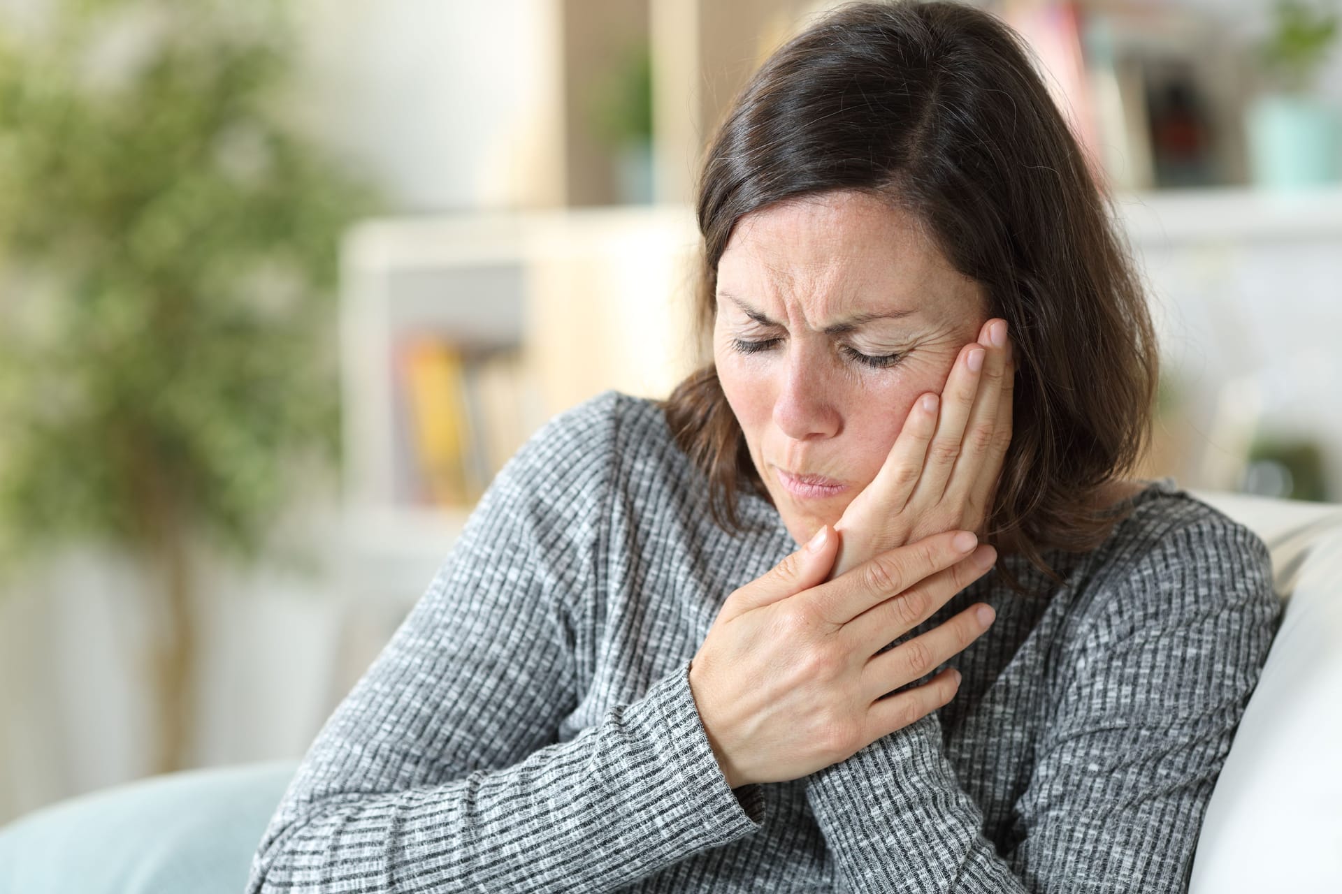 Frau mit Gesichtsschmerzen: Liegt eine bestimmte anatomische Anomalie vor, können bestimmte Kopfbewegungen Schmerzen im Gesicht, im Kiefer- oder Ohrbereich auslösen.