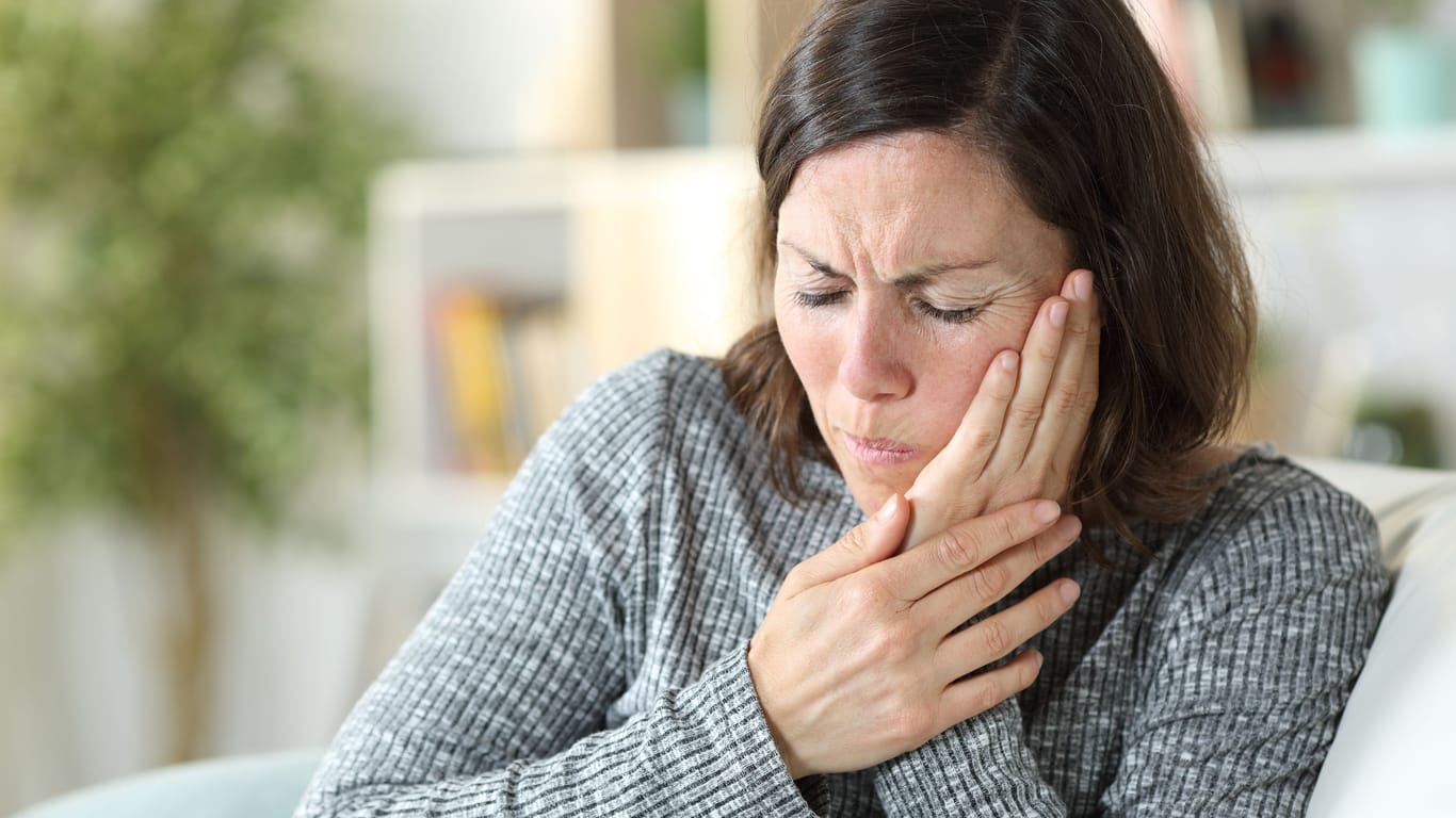 Frau mit Gesichtsschmerzen: Liegt eine bestimmte anatomische Anomalie vor, können bestimmte Kopfbewegungen Schmerzen im Gesicht, im Kiefer- oder Ohrbereich auslösen.