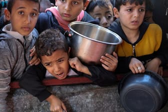 Kinder stehen vor eine Essensausgabe in Gaza an: Hilfsorganisationen warnen vor einer Hungersnot in Gaza. Um das abzuwenden, werfen Jordanien und die USA Hilfsgüter aus der Luft ab.