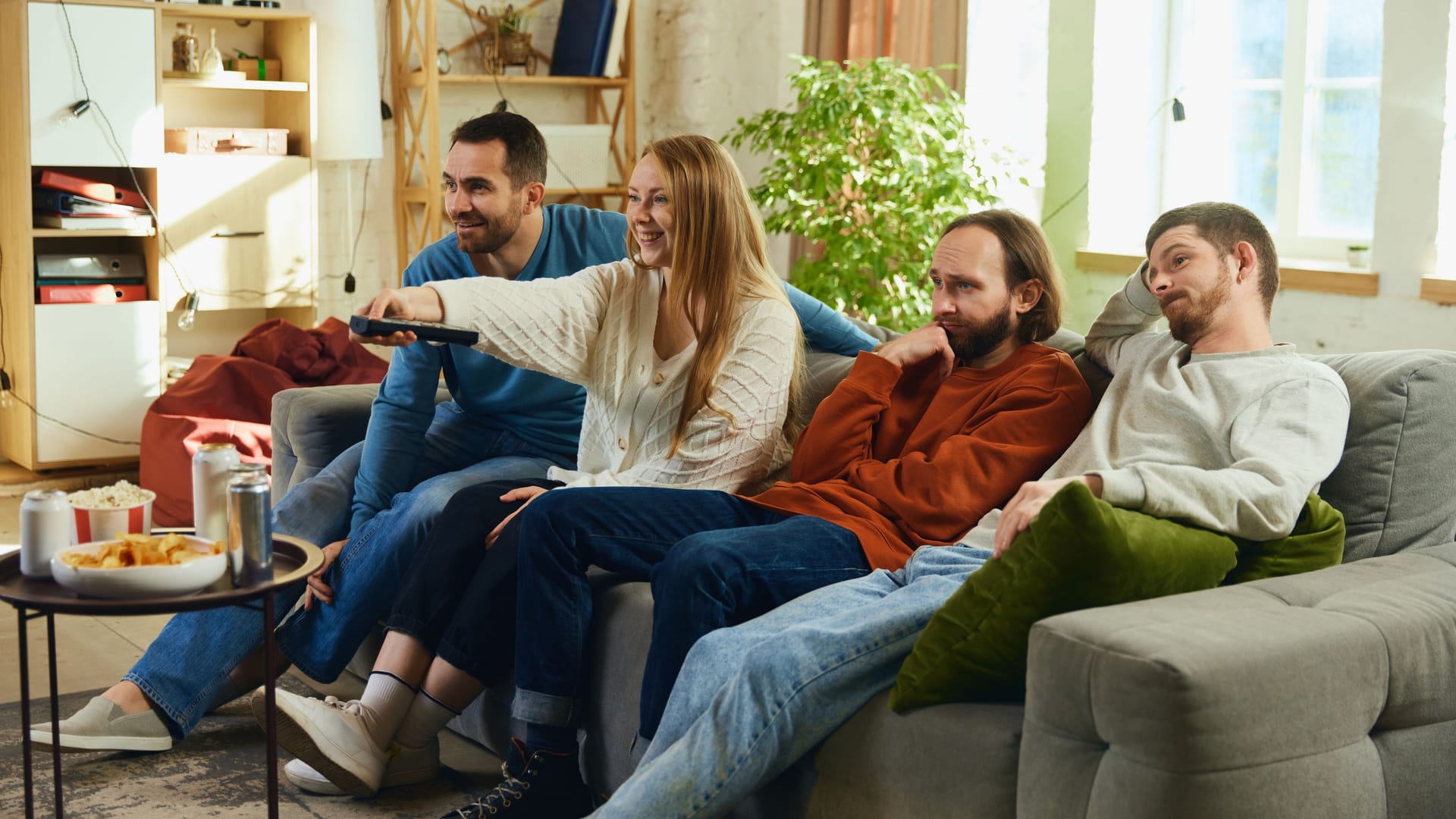 One young woman in friends young male company switches decisive soccer game seated on couch in living room at home. Concept of leisure activity.