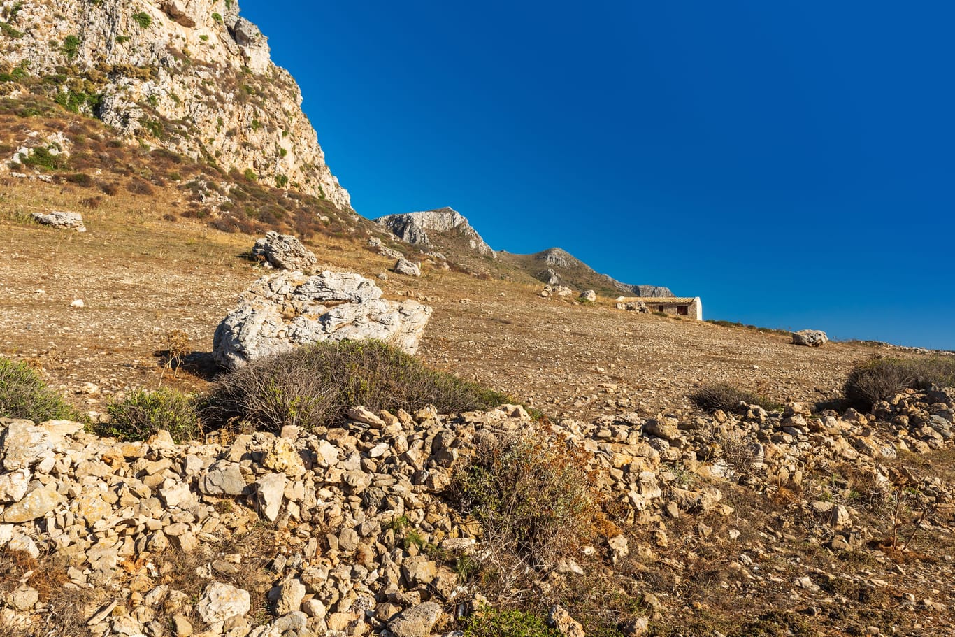 Landscape with rocky ground, rock, wall and house. Sicily