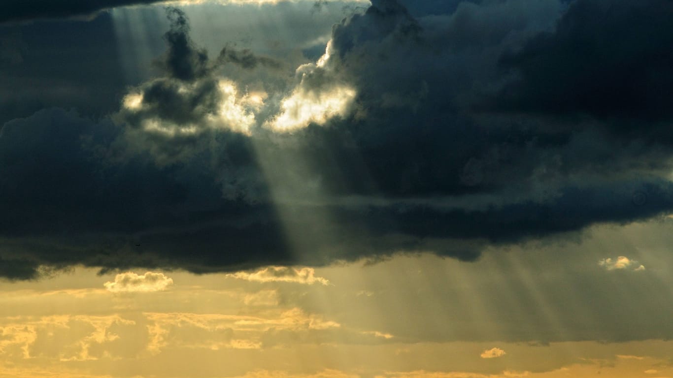 Sonne bricht durch dichte Wolken (Symbolbild): Am Sonntag soll stellenweise die Sonne herauskommen.