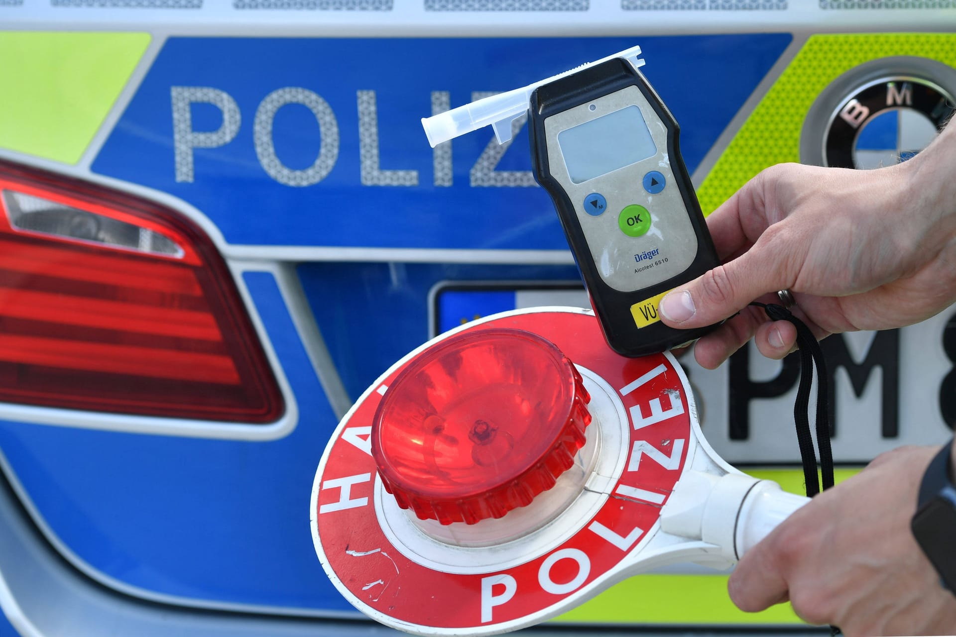 Ein Polizist hält ein Atemalkoholgerät sowie eine Kelle in der Hand (Symbolbild): Bei dem Mann wurde über 1 Promille gemessen.