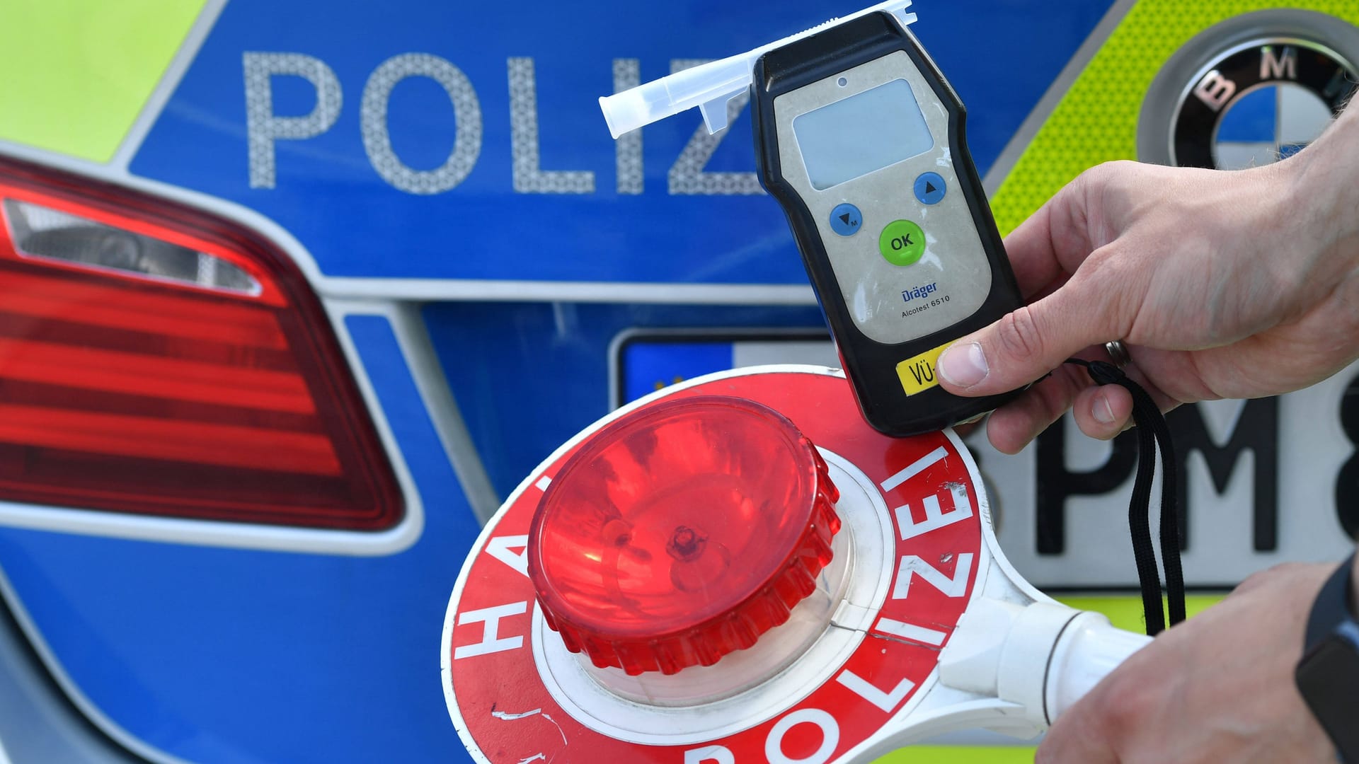 Ein Polizist hält ein Atemalkoholgerät sowie eine Kelle in der Hand (Symbolbild): Bei dem Mann wurde über 1 Promille gemessen.