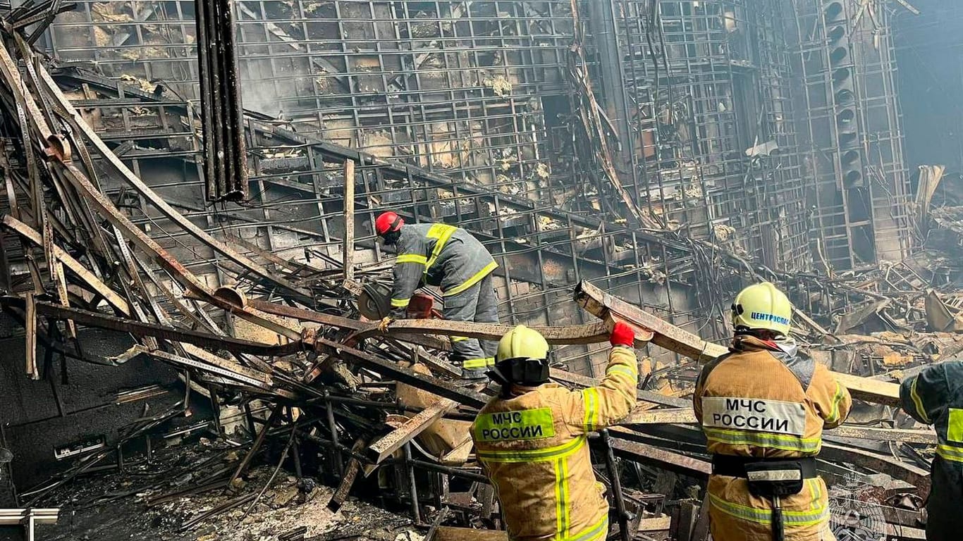 Feuerwehrleute durchsuchen die Trümmer der weitgehend abgebrannten Halle nahe Moskau.