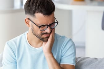 Mann mit Zahnschmerzen: Karies kann zu Zahnschmerzen führen. Doch ist sie auch ansteckend?