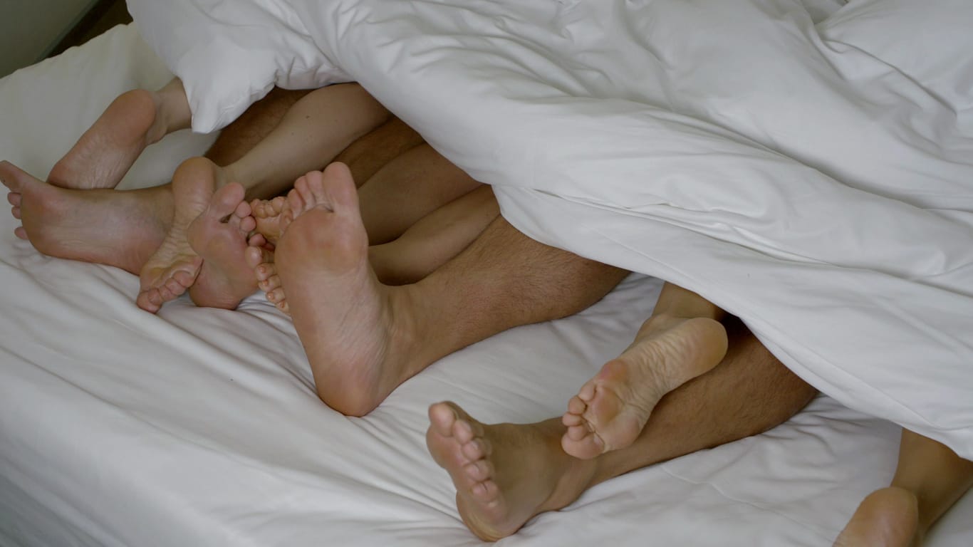Die Füße mehrerer Menschen schauen unter der Bettdecke hervor: Bei einer Sex-Party betäubte der Veranstalter zwei Frauen und wurde dafür verurteilt.