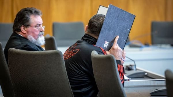 Essen: Der Angeklagte sitzt im Landgericht und verbirgt sein Gesicht hinter einem Aktenordner, links sitzt sein Rechtsanwalt Victor Berger. Essen: Der Angeklagte sitzt im Landgericht und verbirgt sein Gesicht hinter einem Aktenordner, links sitzt sein Rechtsanwalt Victor Berger.