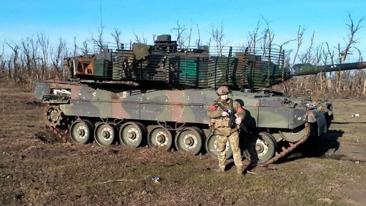 Ein russischer Soldat zeigt sich vor dem zurückgelassenen Leopard 2 in der Ostukraine.