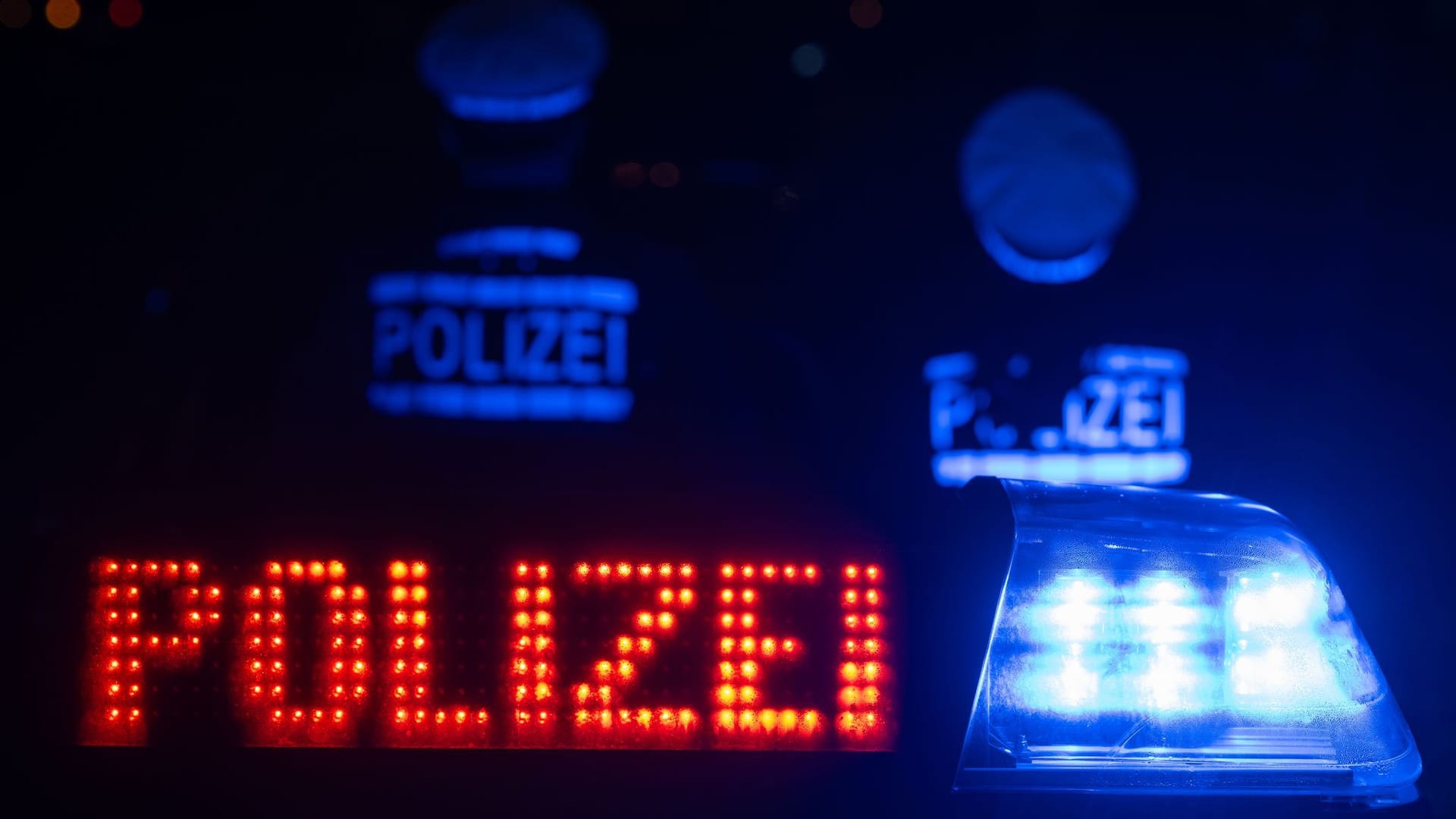 Zwei Polizisten stehen vor einem Polizeifahrzeug (Symbolfoto): Zu dem oder den Täter war zunächst nichts bekannt.