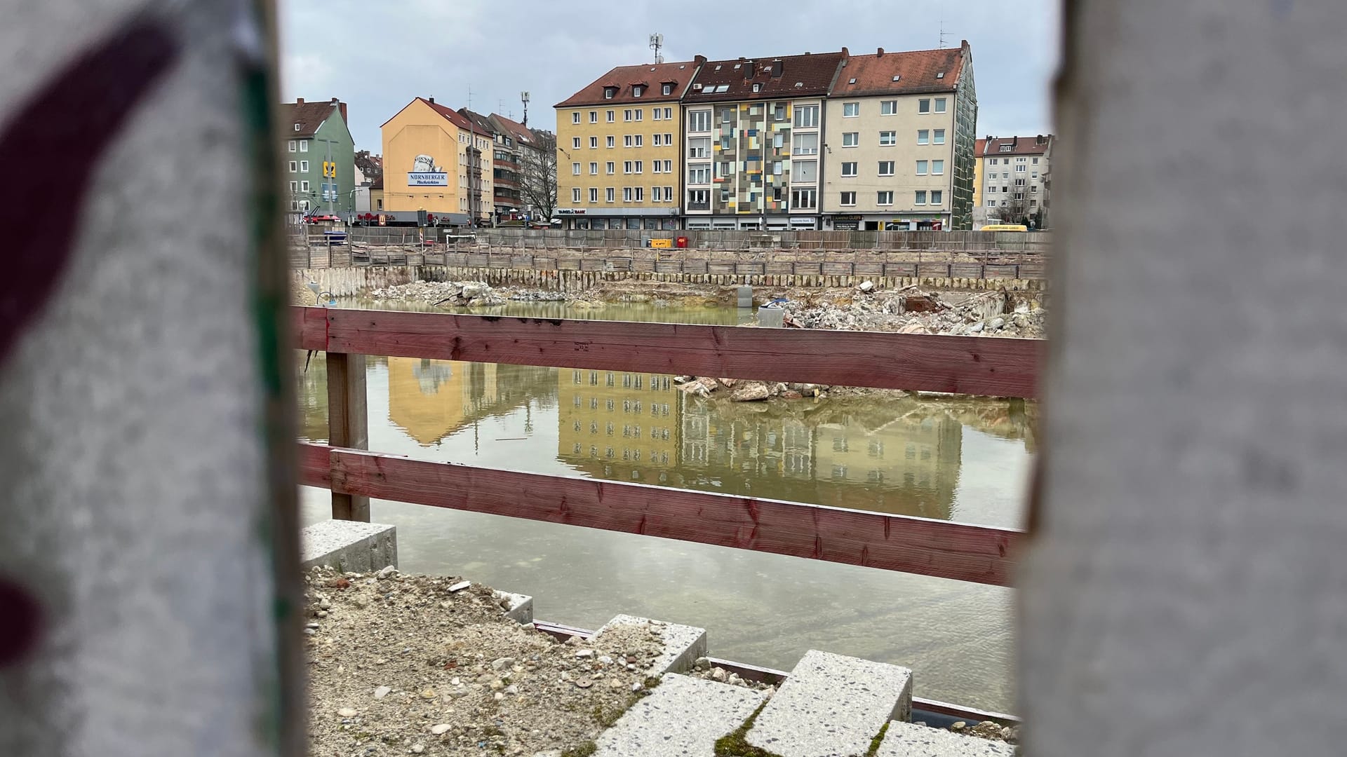 Um einen Blick auf die Baugrube zu erhaschen, muss man durch ein Loch in den Bauzäunen schauen: Im Februar wurde ein Teil der Zäune zurückgebaut, damit der Durchgang zwischen Breitscheid- und Wiesenstraße möglich ist.