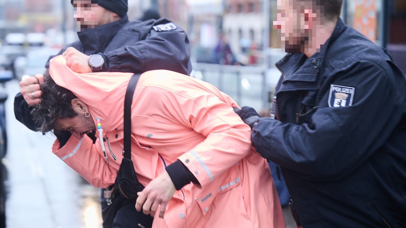 Berliner Polizisten halten einen Unterstützer der "Letzten Generation" an der Warschauer Brücke fest