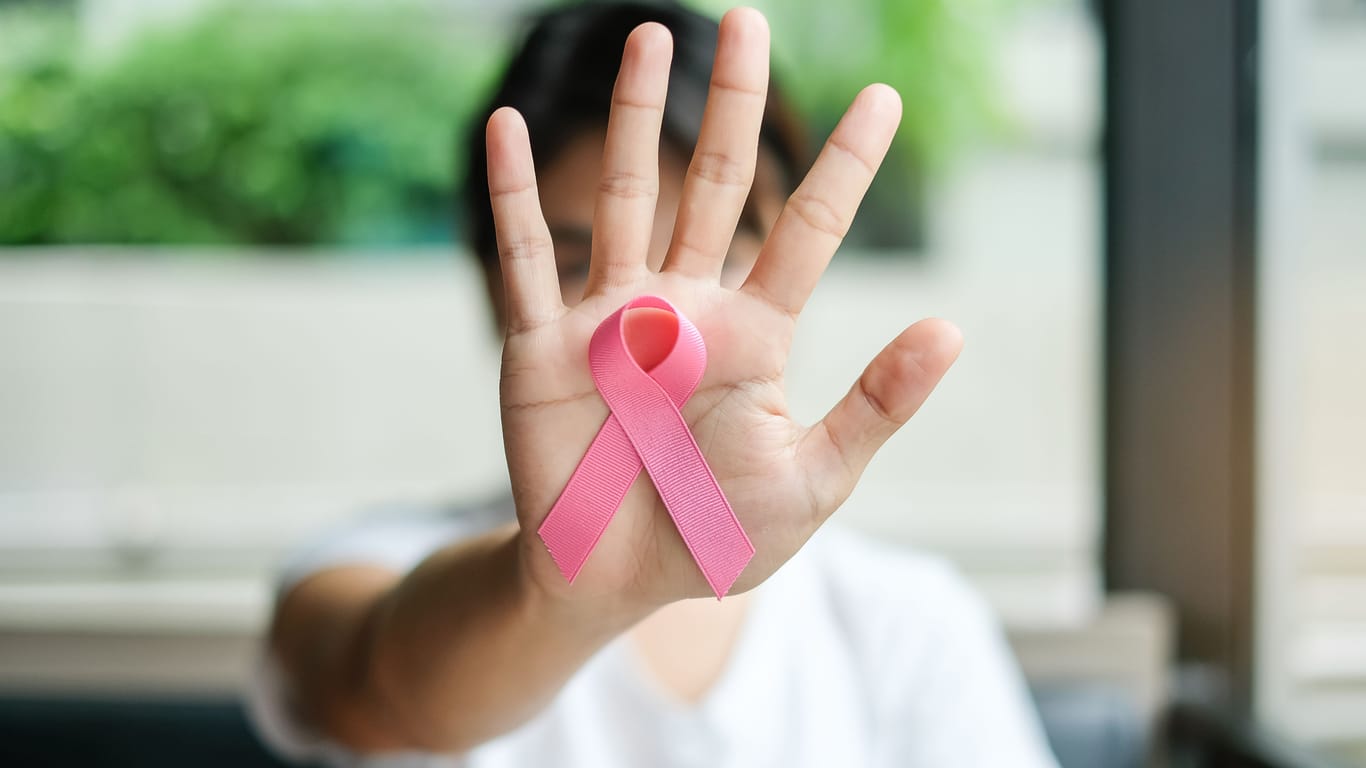 Eine Frau zeigt die Brustkrebs-Schleife.