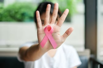 Eine Frau zeigt die Brustkrebs-Schleife.