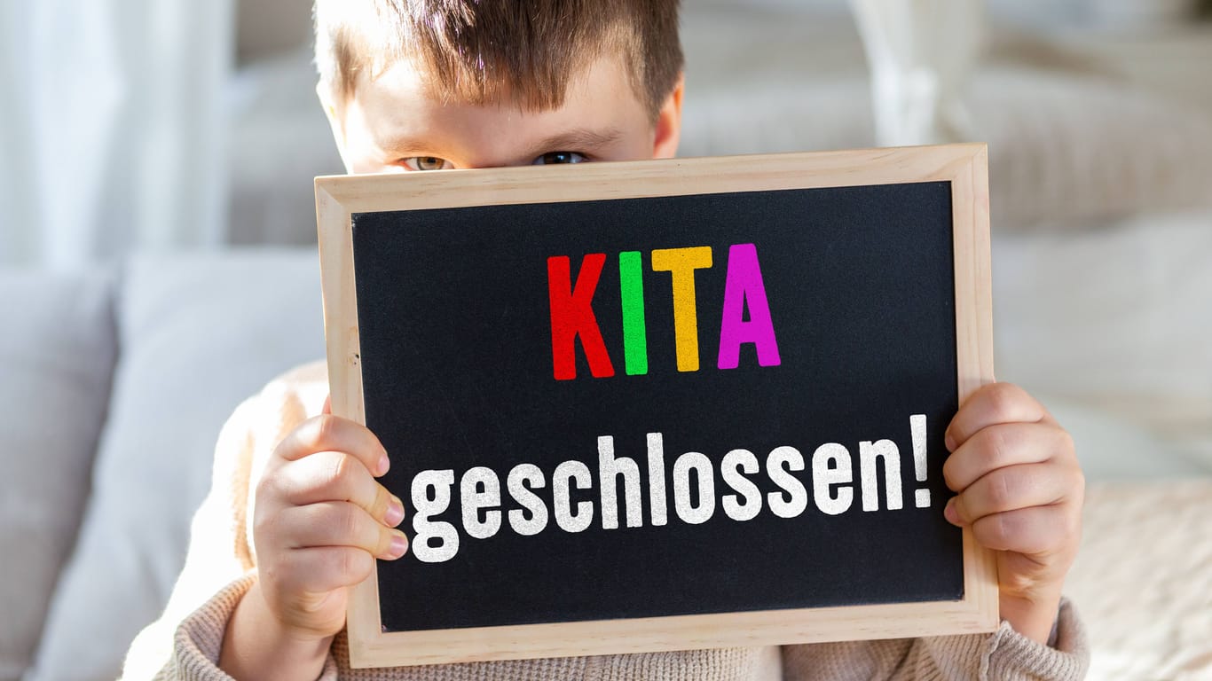 Ein Junge hält ein Schild mit "Kita geschlossen" (Montage): In der Region Hannover macht sich zunehmend Unmut bei Eltern breit.