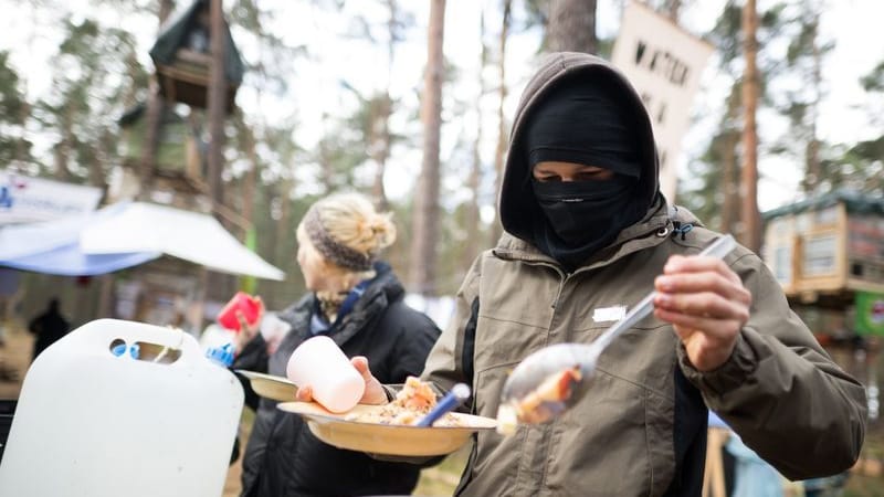 Ein Aktivist nimmt sich in einem Protestcamp nahe der Tesla-Gigafactory eine Portion Porridge.